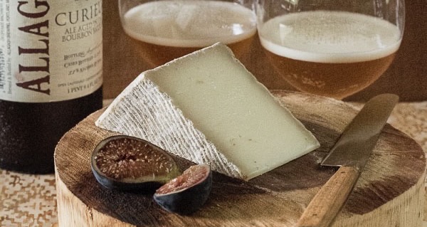 Cheese on a board with a knife and glasses of wine