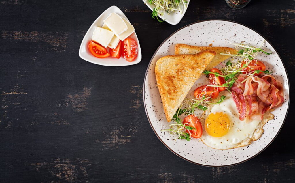A top-down view of a classic breakfast plate with eggs, bacon, and toast