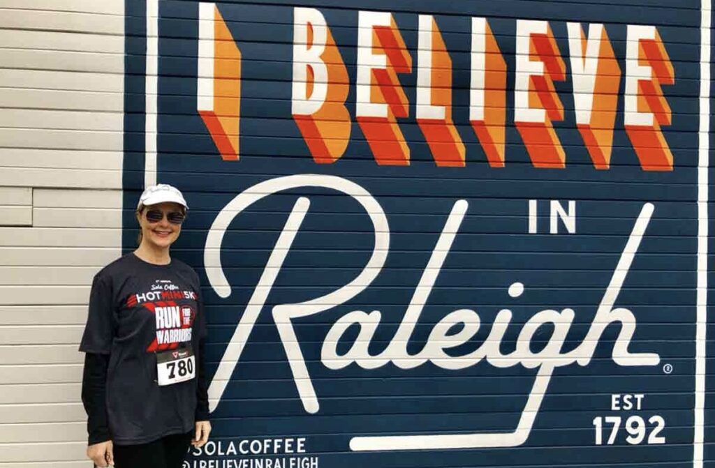 A girl stands near a painted coffee shop sign on the wall